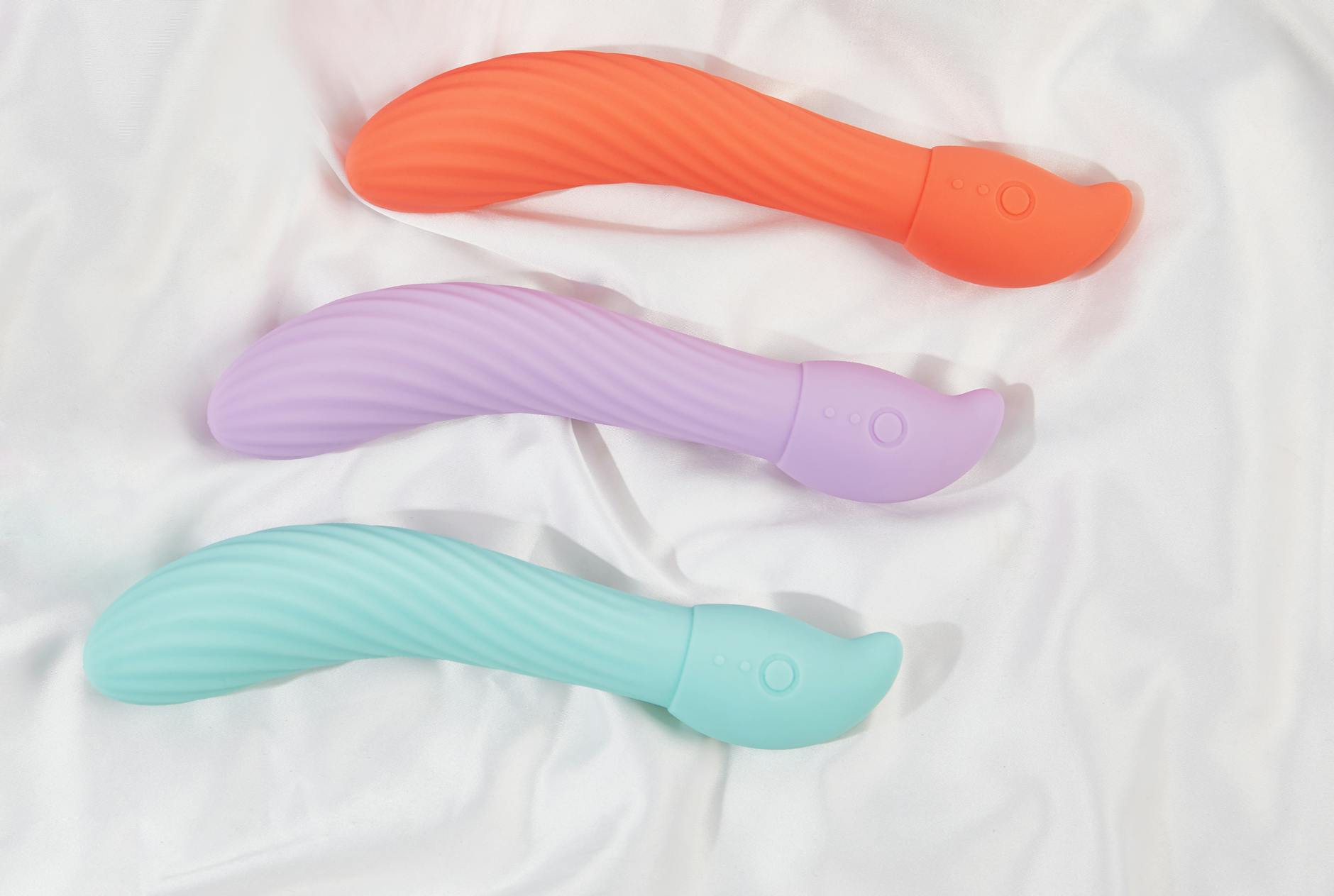 A teal lemon vibrator on white silk fabric, representing safe, gentle pleasure during healing.