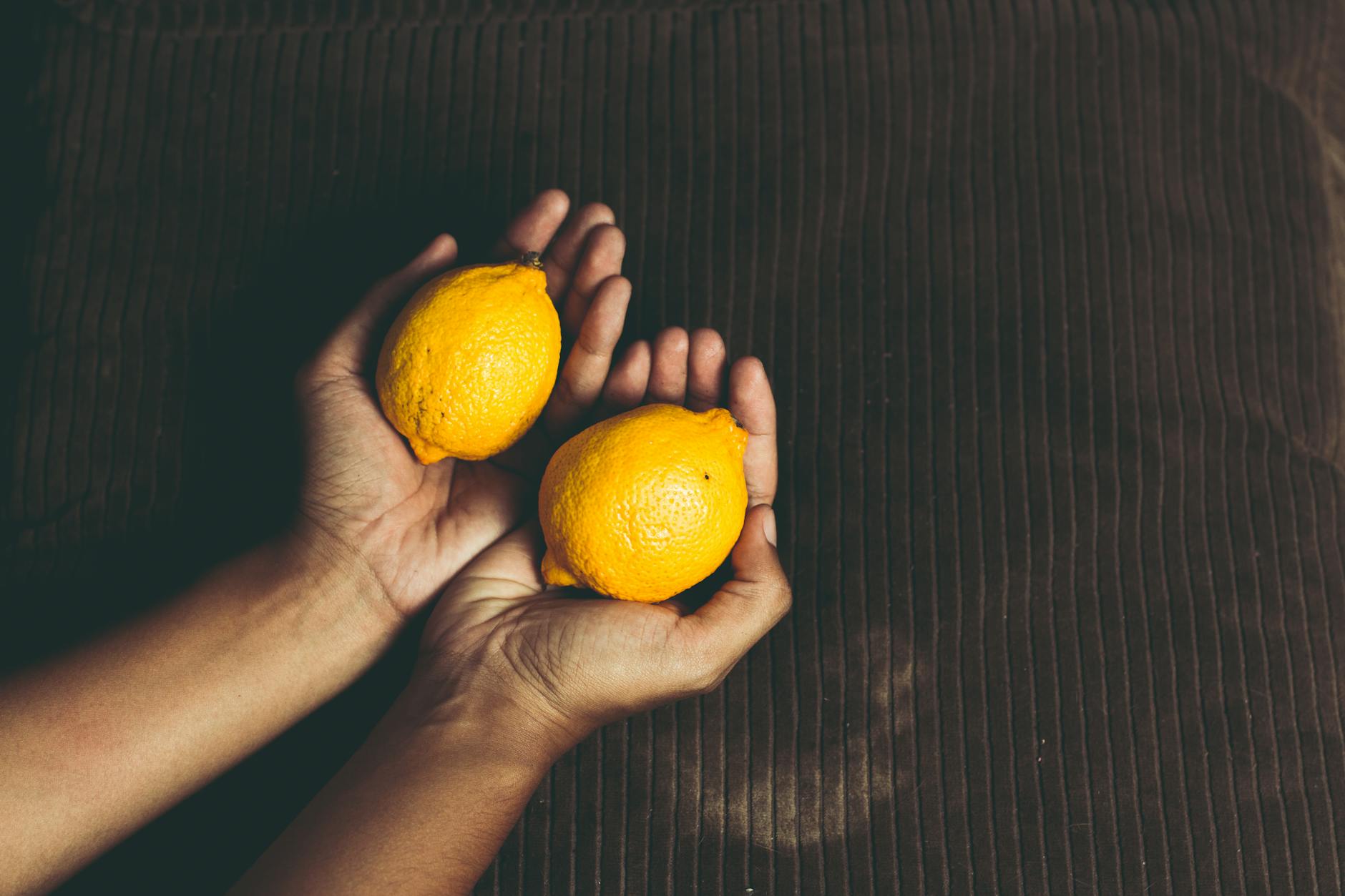 Two fresh lemons held in cupped hands, representing gentle yet powerful sensation