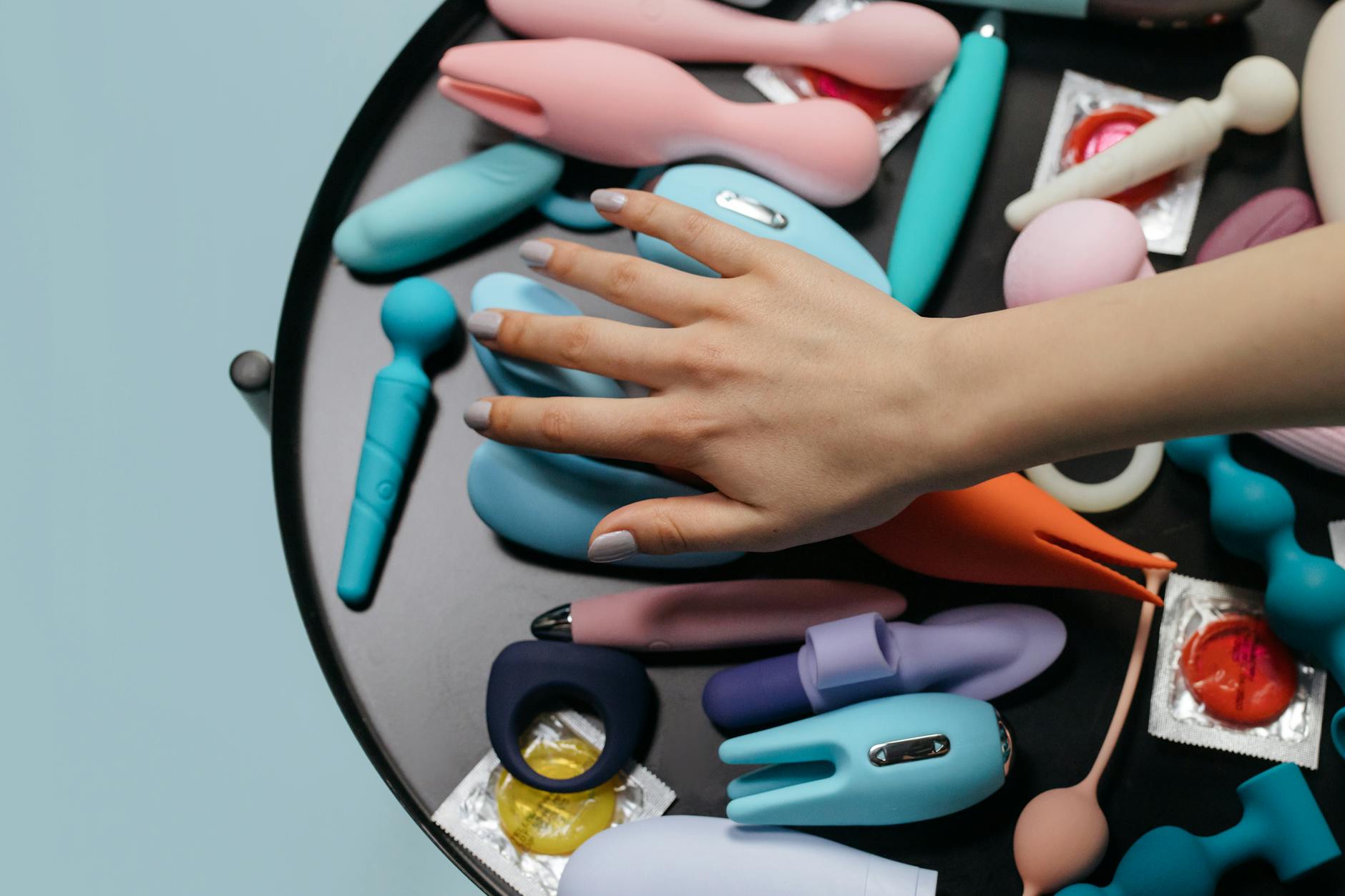 Person holding clitoral vibrators thoughtfully, representing intimate wellness during recovery