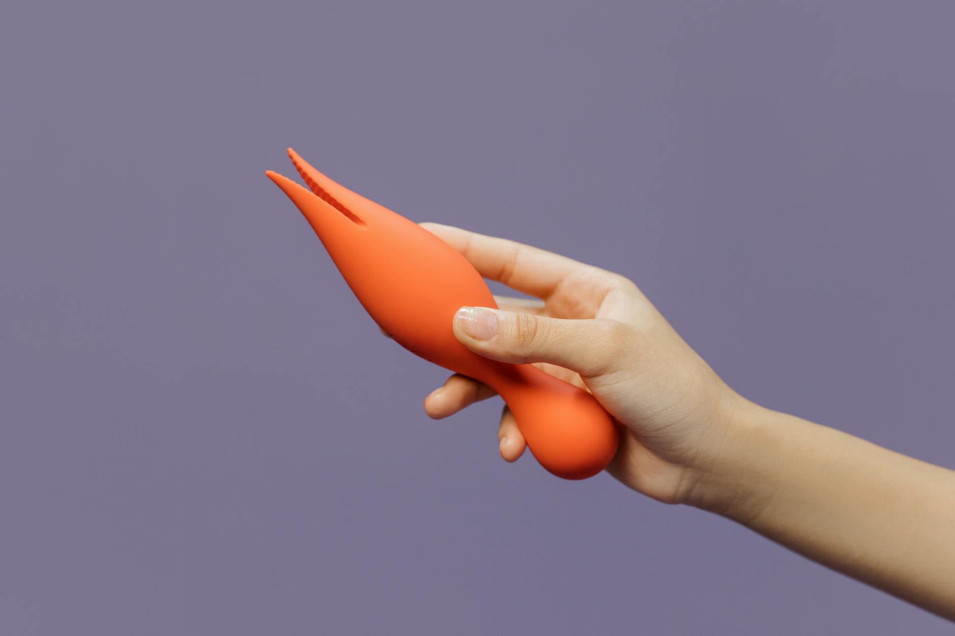 A hand holding a vibrator against a purple backdrop, showcasing modern sensuality and pleasure
