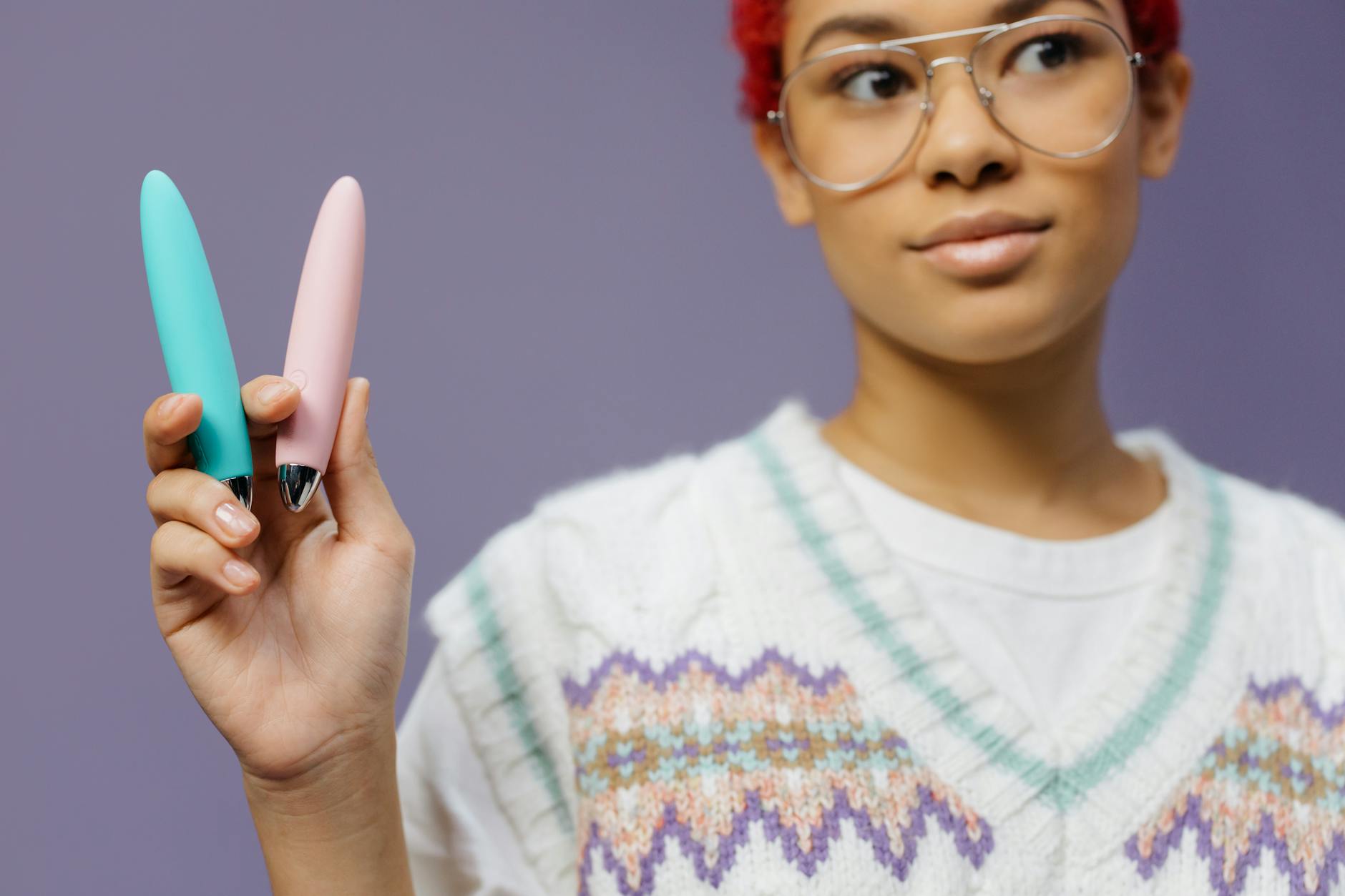 A hand holding a lemon vibrator against a purple background, showing the device ready for use