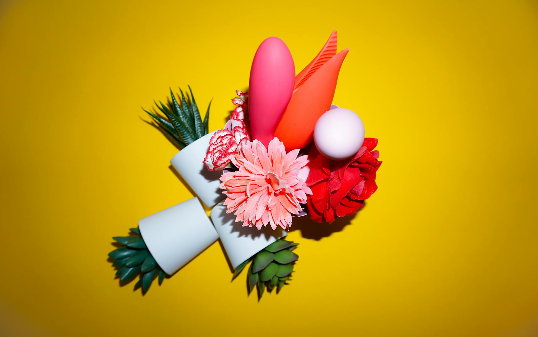 Hands holding pink and blue silicone vibrators against a pastel background, representing intimate self-care without pressure.