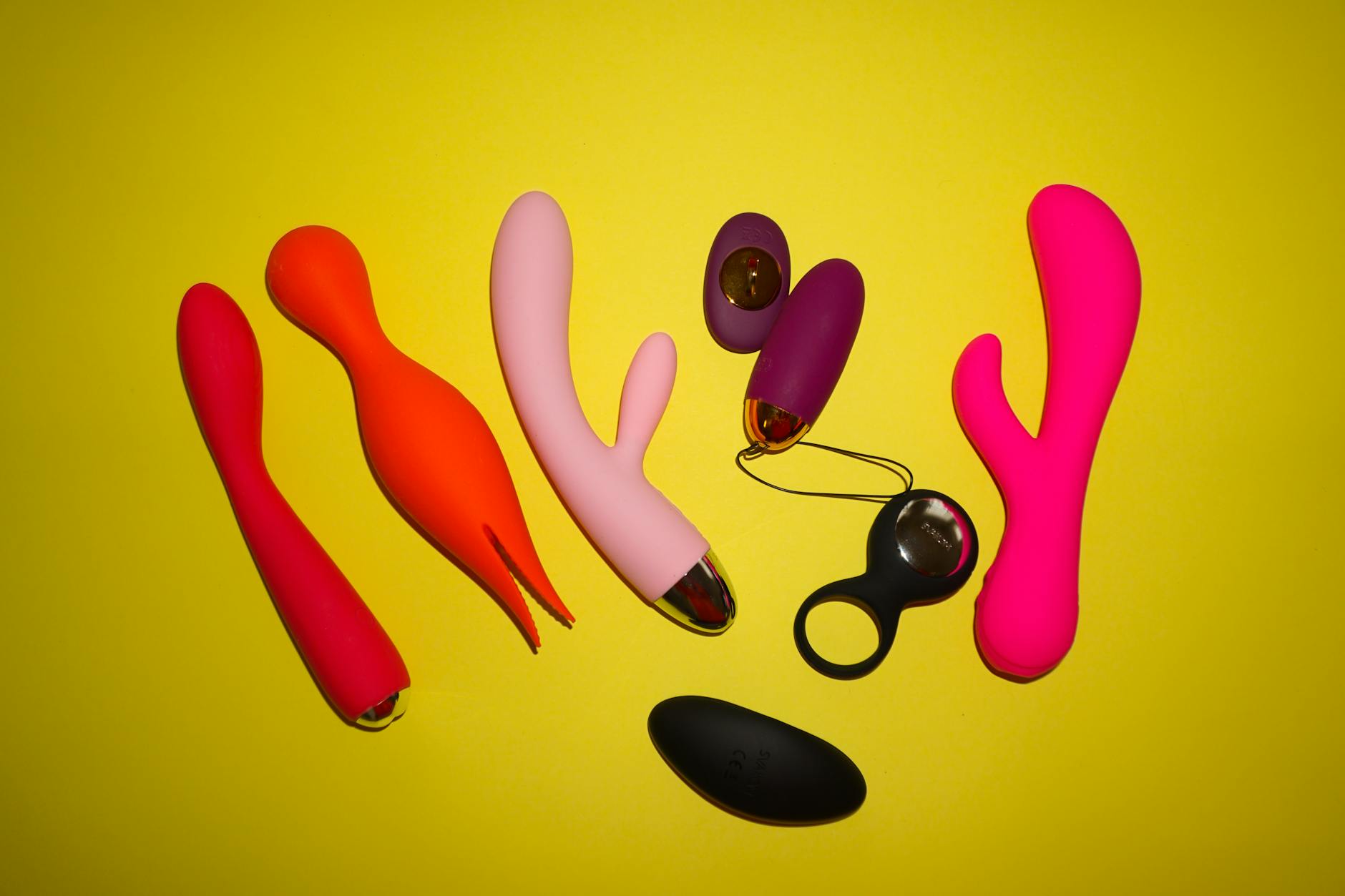 Woman holding blue and pink silicone vibrators in a thoughtful pose